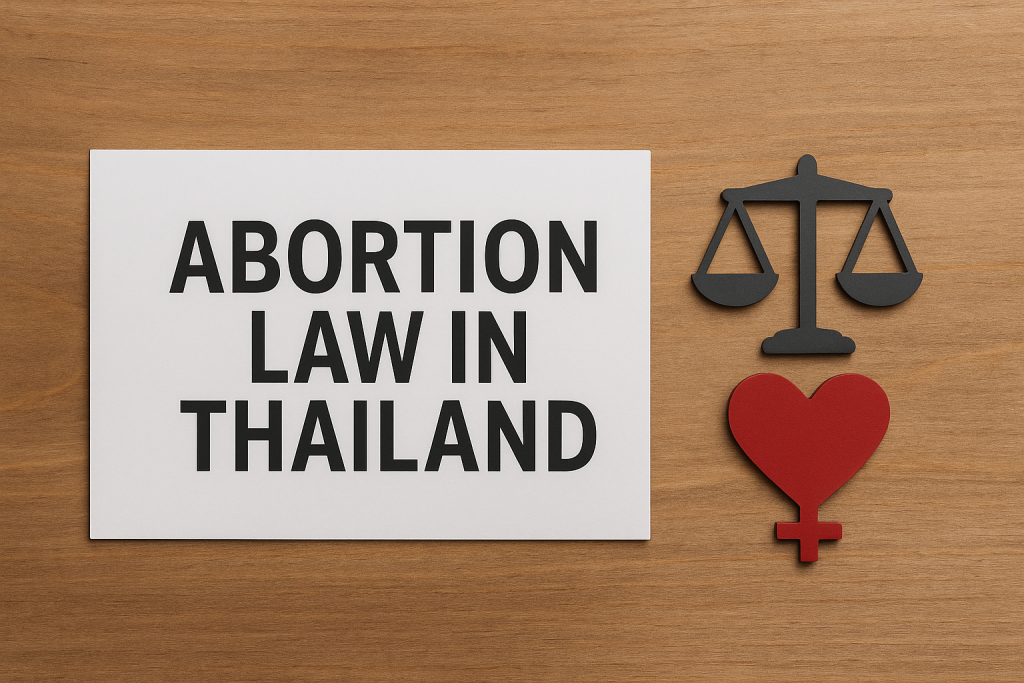 A white sign says “Abortion Law in Thailand.” It is on a wooden background. The sign has symbols of justice and women’s rights. These symbols show the legal and ethical sides of abortion in Thailand.